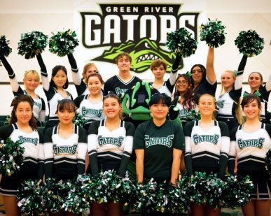 group of smiling cheerleaders in green uniforms