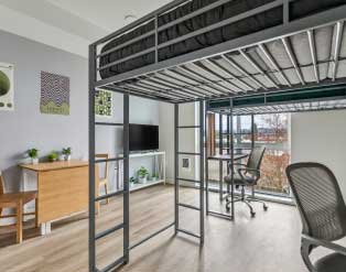 dorm room with bunk bed and desks