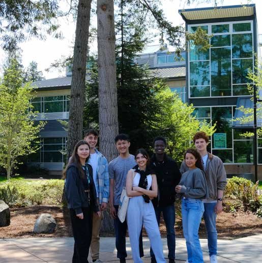 group of students in front of trees and modern building