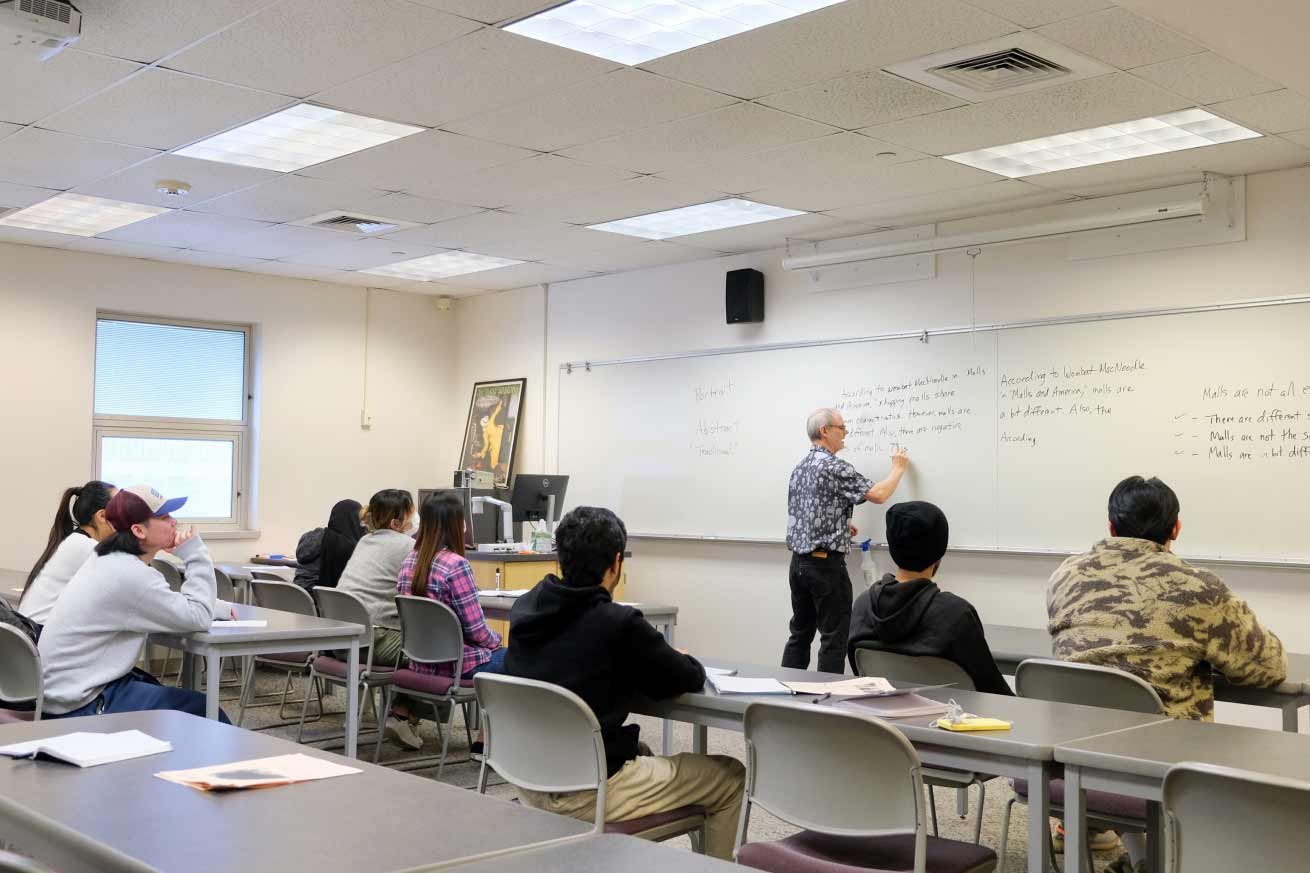 a class with male instructor who is writing on the board